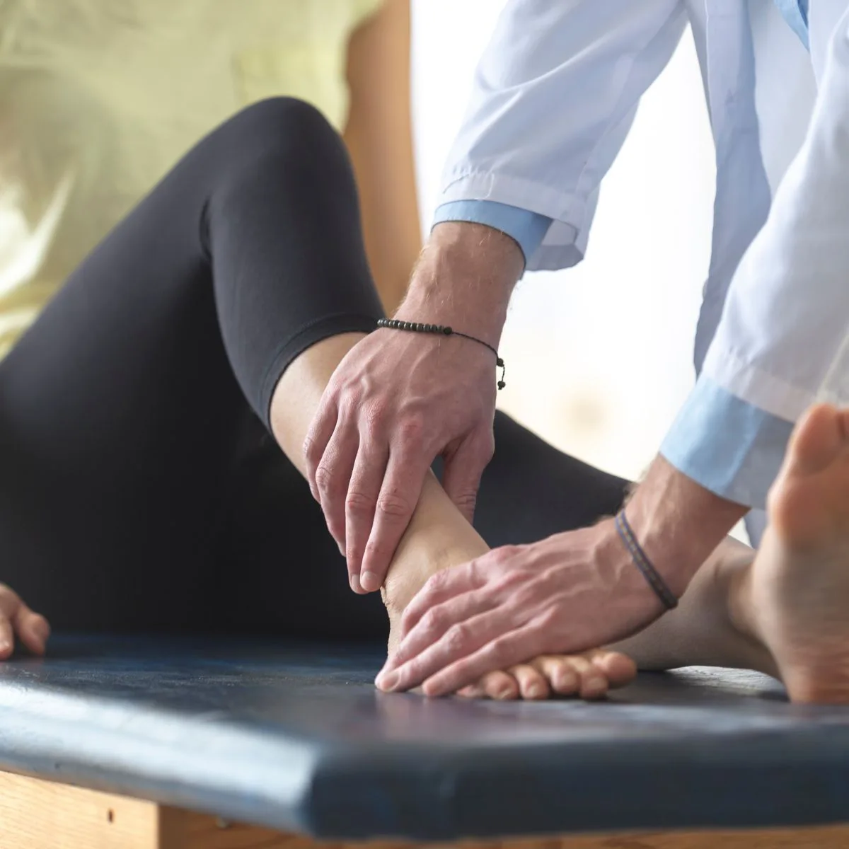 Therapist examining a patient’s ankle on a treatment table