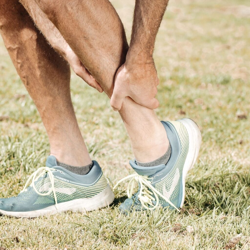 Runner holding his ankle outdoors on the grass