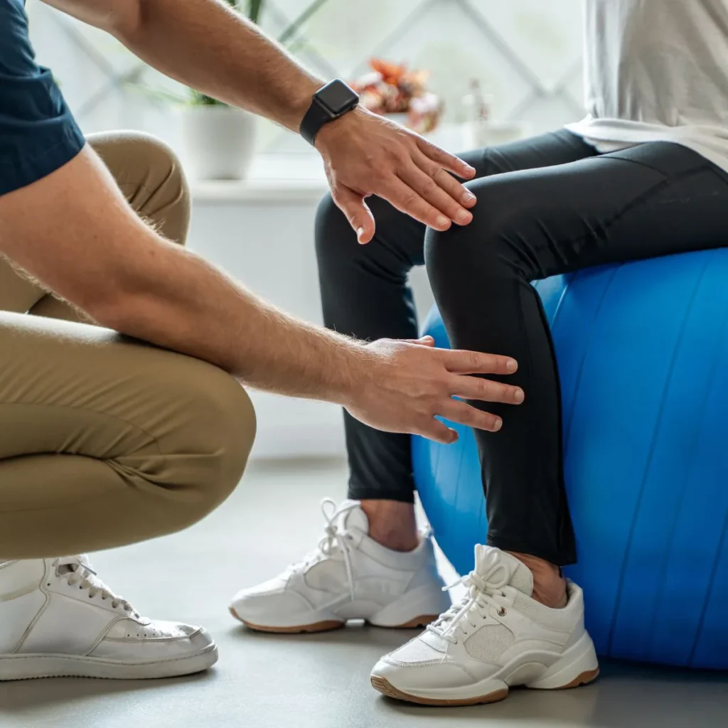 Therapist guiding patient’s knee movement on an exercise ball