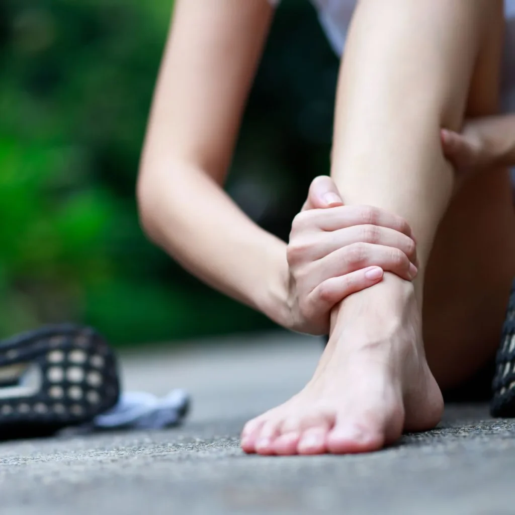 Person clutching their ankle outdoors