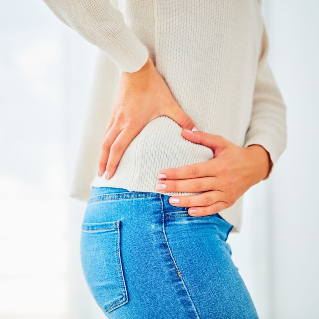 Woman in jeans pressing her hip while standing