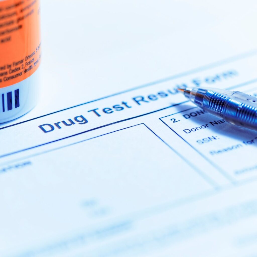 A close-up of a drug test result form with a pen and pill bottle