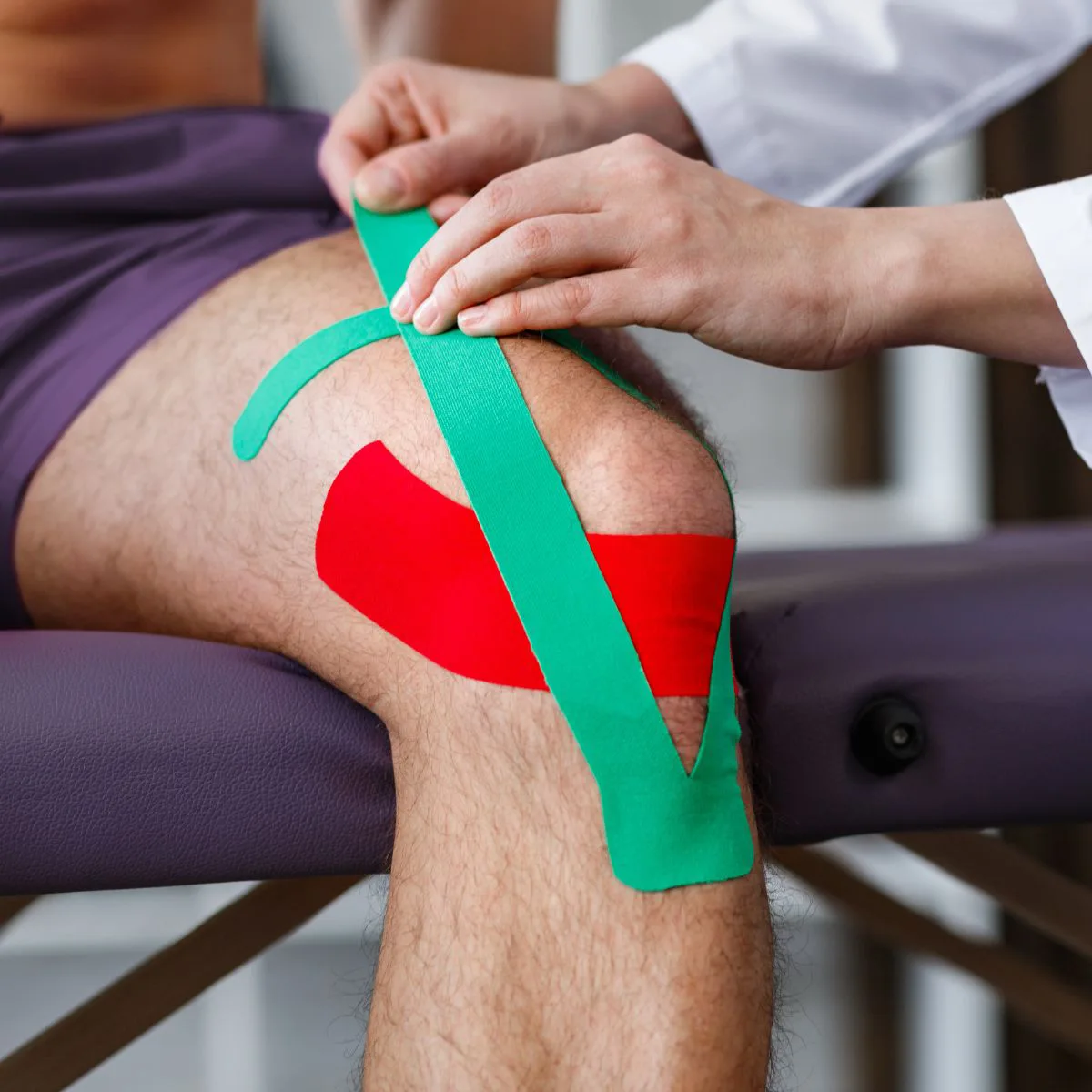 Therapist applying kinesiology tape to a patient’s knee