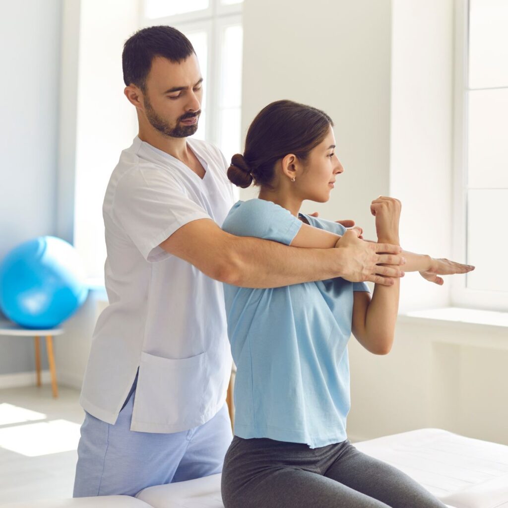 A physical therapist assists a woman stretching her arm