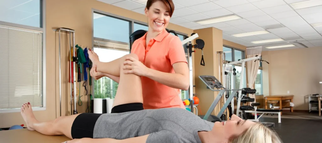 Physical therapist assisting a woman with a leg stretch on a table